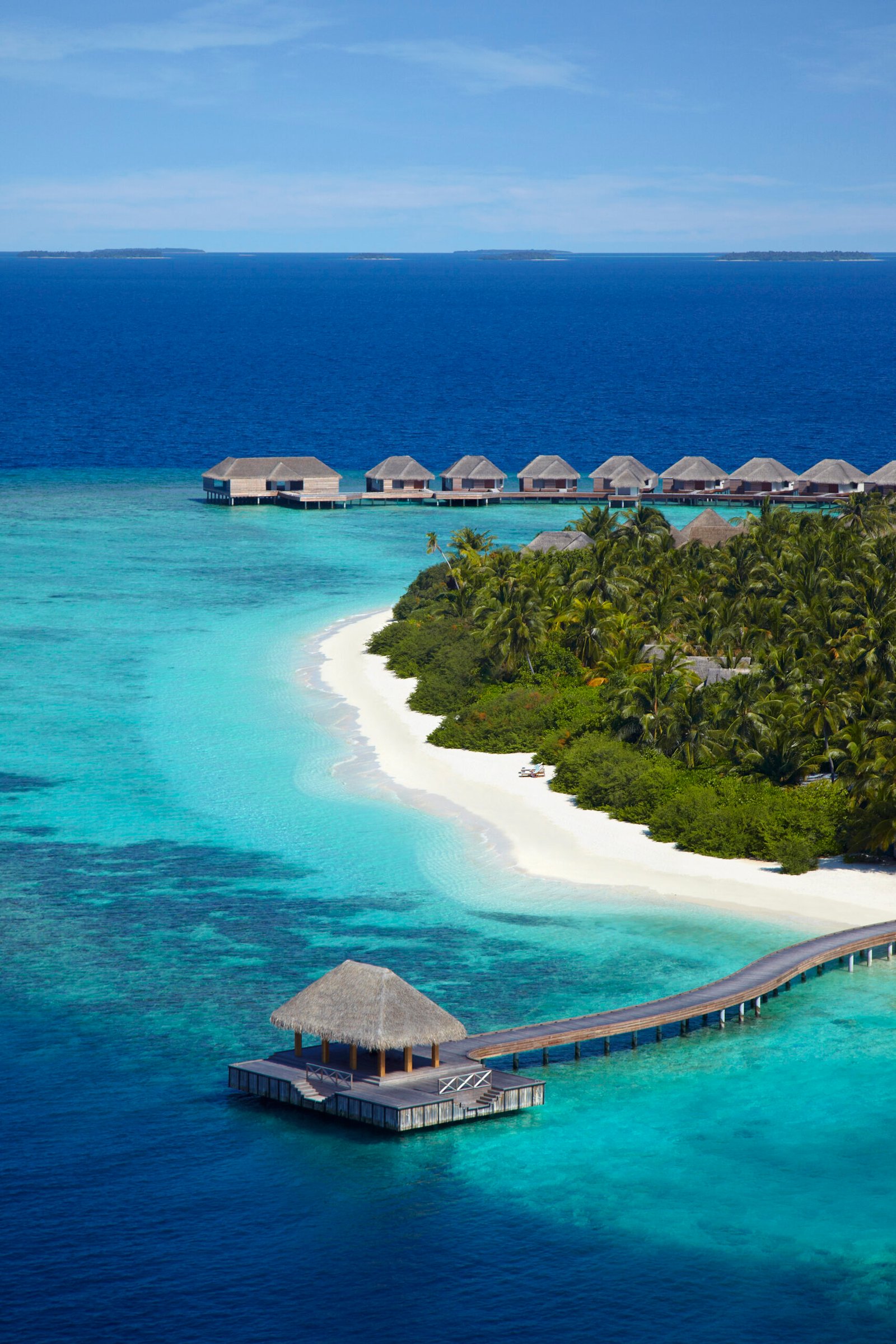 Curving white-sand beach and overwater jetty pavilion at Dusit Thani Maldives, Baa Atoll