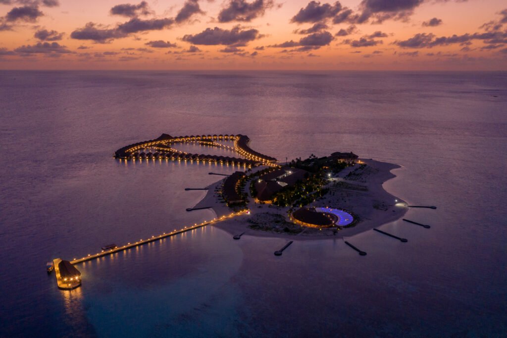 Aerial dusk view of Cinnamon Velifushi Maldives overwater villas, Vaavu Atoll