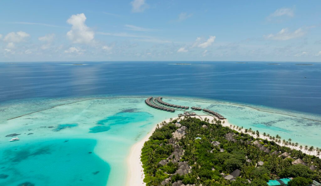 Sun Siyam Iru Fushi hero — aerial view of the island and overwater villas, Noonu Atoll, Maldives