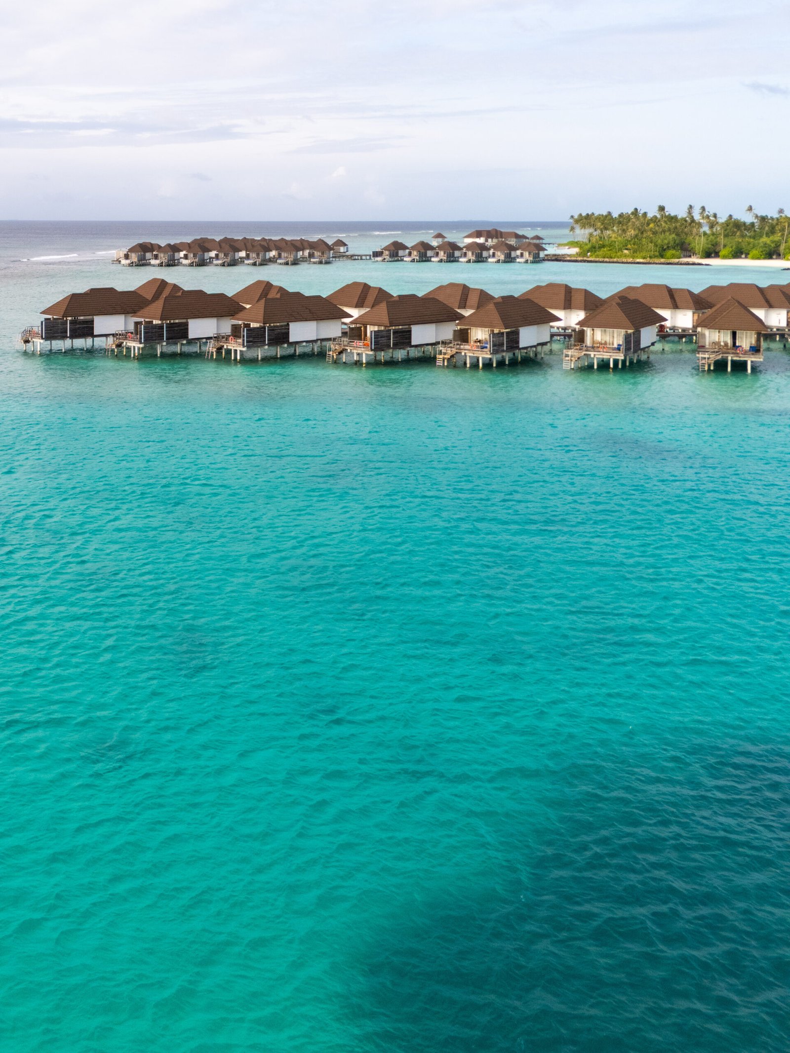 Aerial view of overwater villas across the turquoise lagoon at Sun Siyam Olhuveli, Maldives
