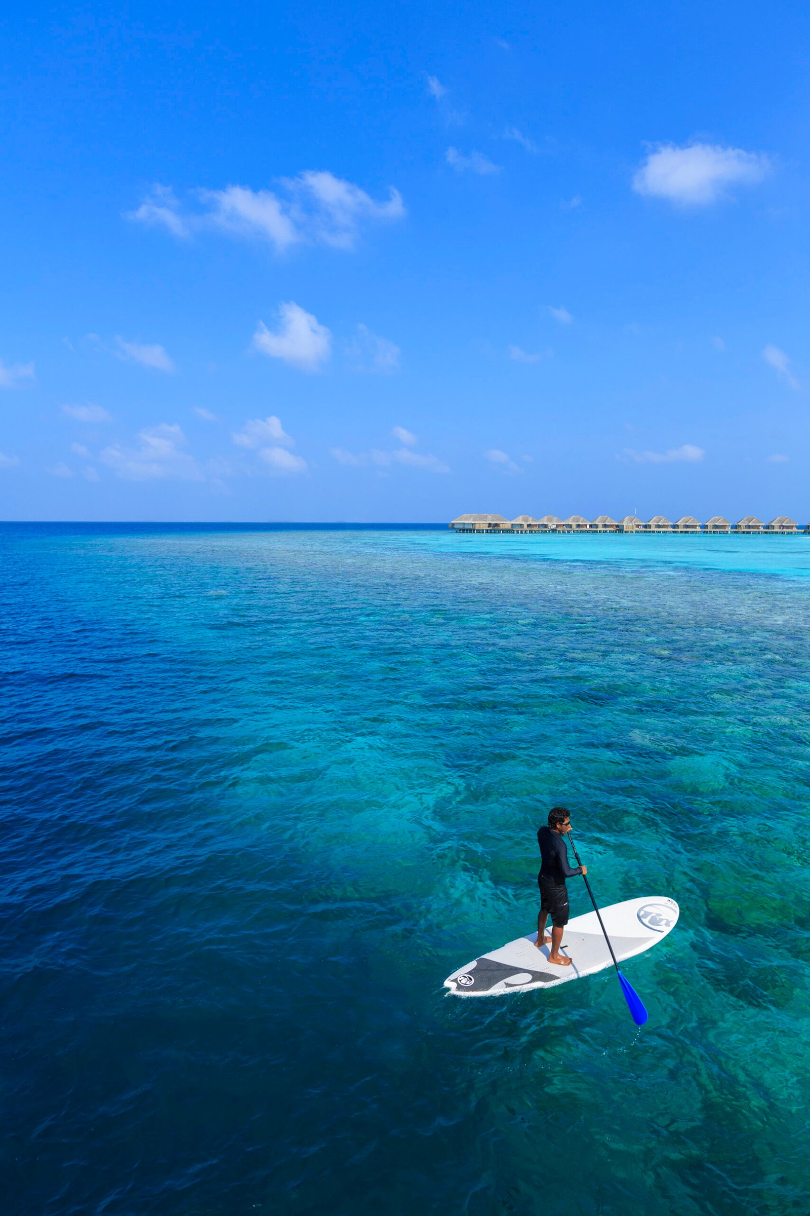 Stand-up paddleboarding near the overwater villas, Dusit Thani Maldives