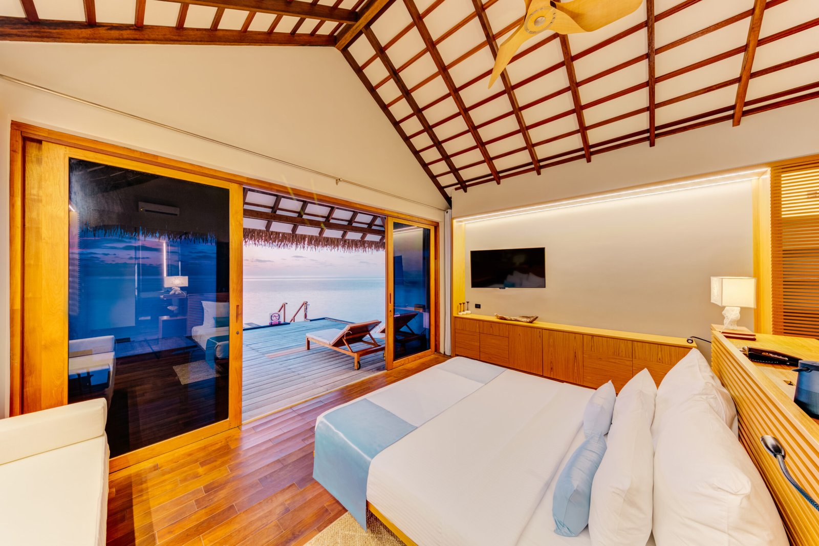 Sunset Water Bungalow bedroom interior with ocean view, Cinnamon Velifushi Maldives