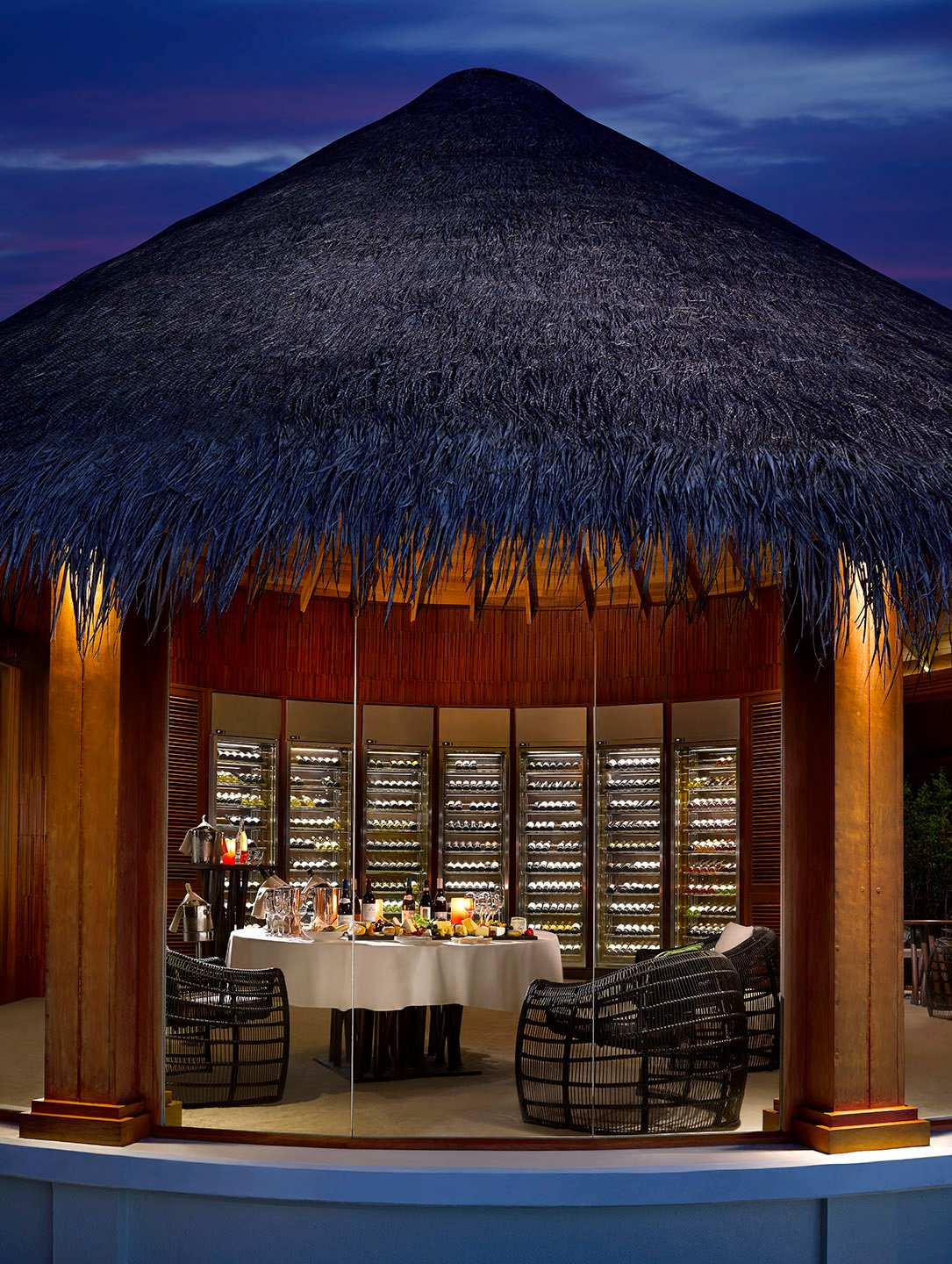 Private wine cellar dining pavilion at dusk, Dusit Thani Maldives