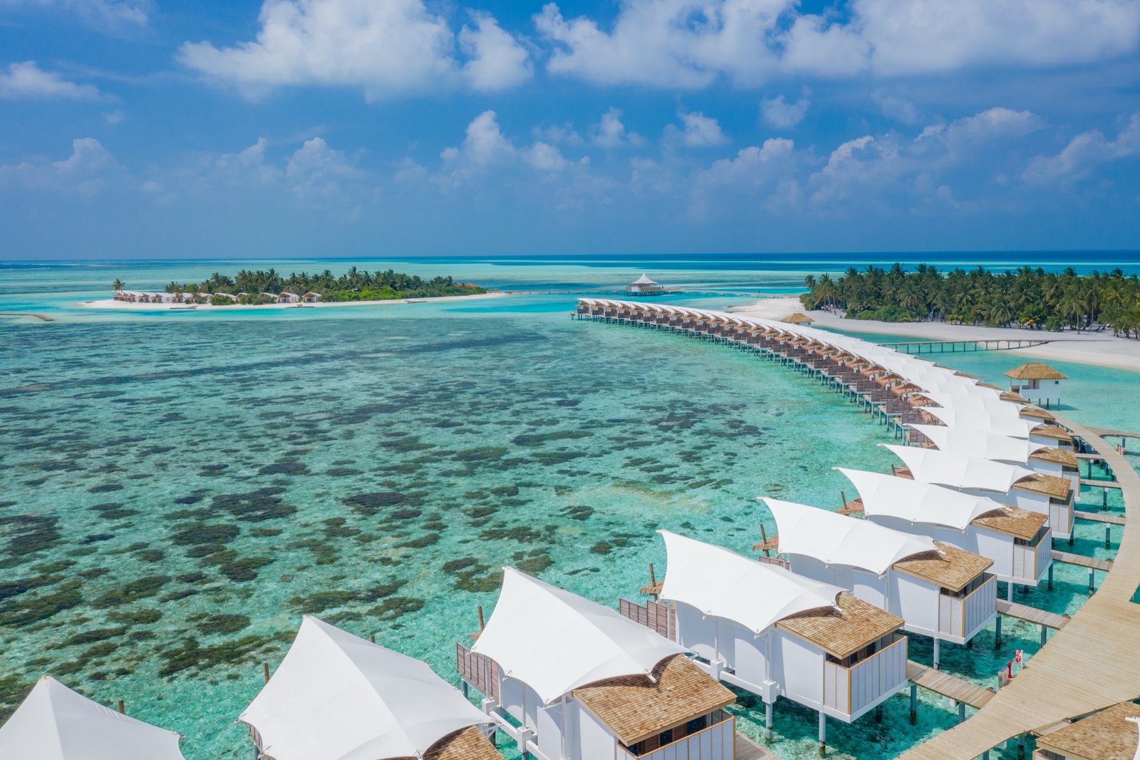 The overwater bungalow arm curving across the lagoon, Cinnamon Hakuraa Huraa Maldives