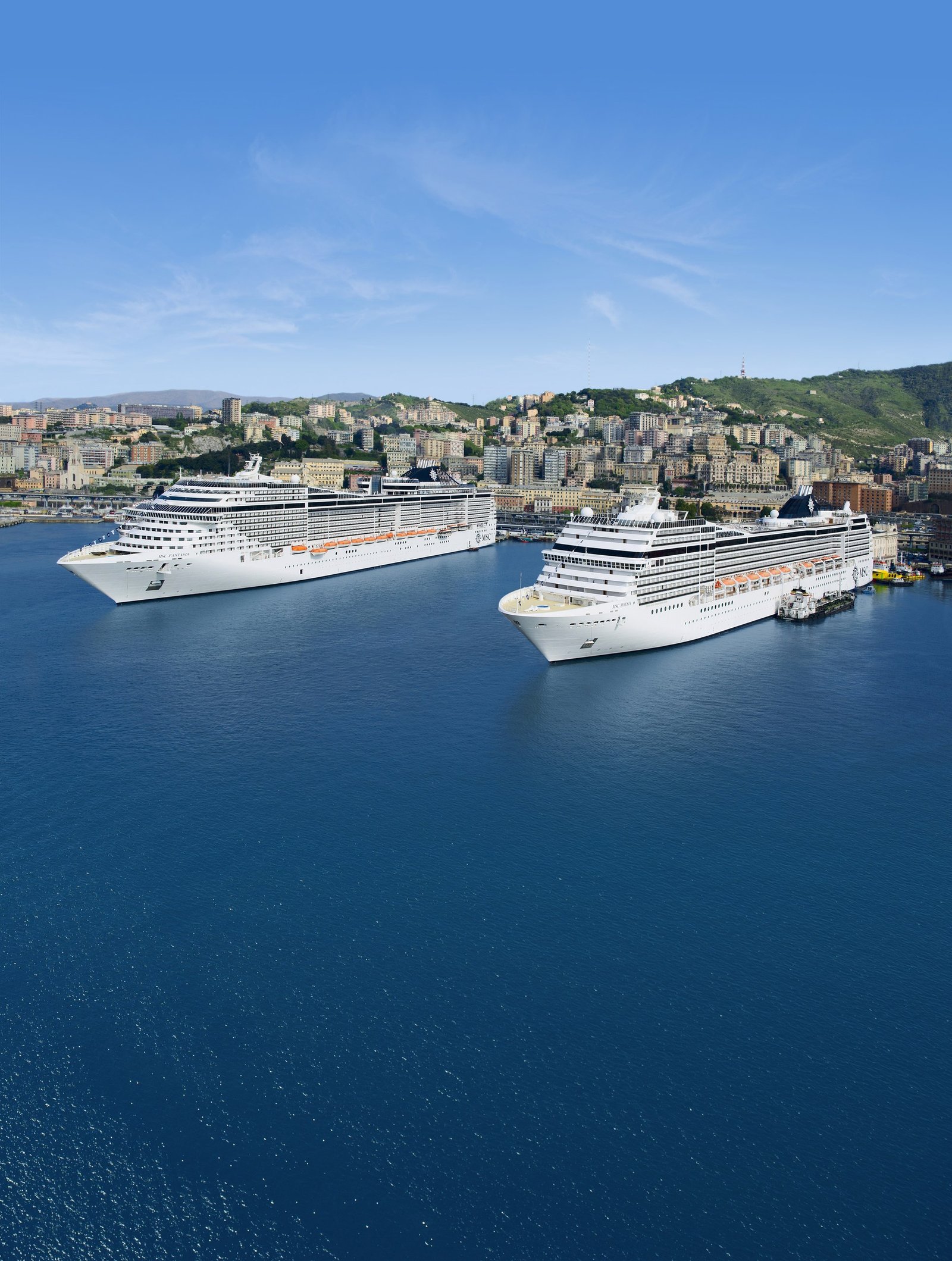 Two MSC Cruises ships berthed below an Italian coastal town