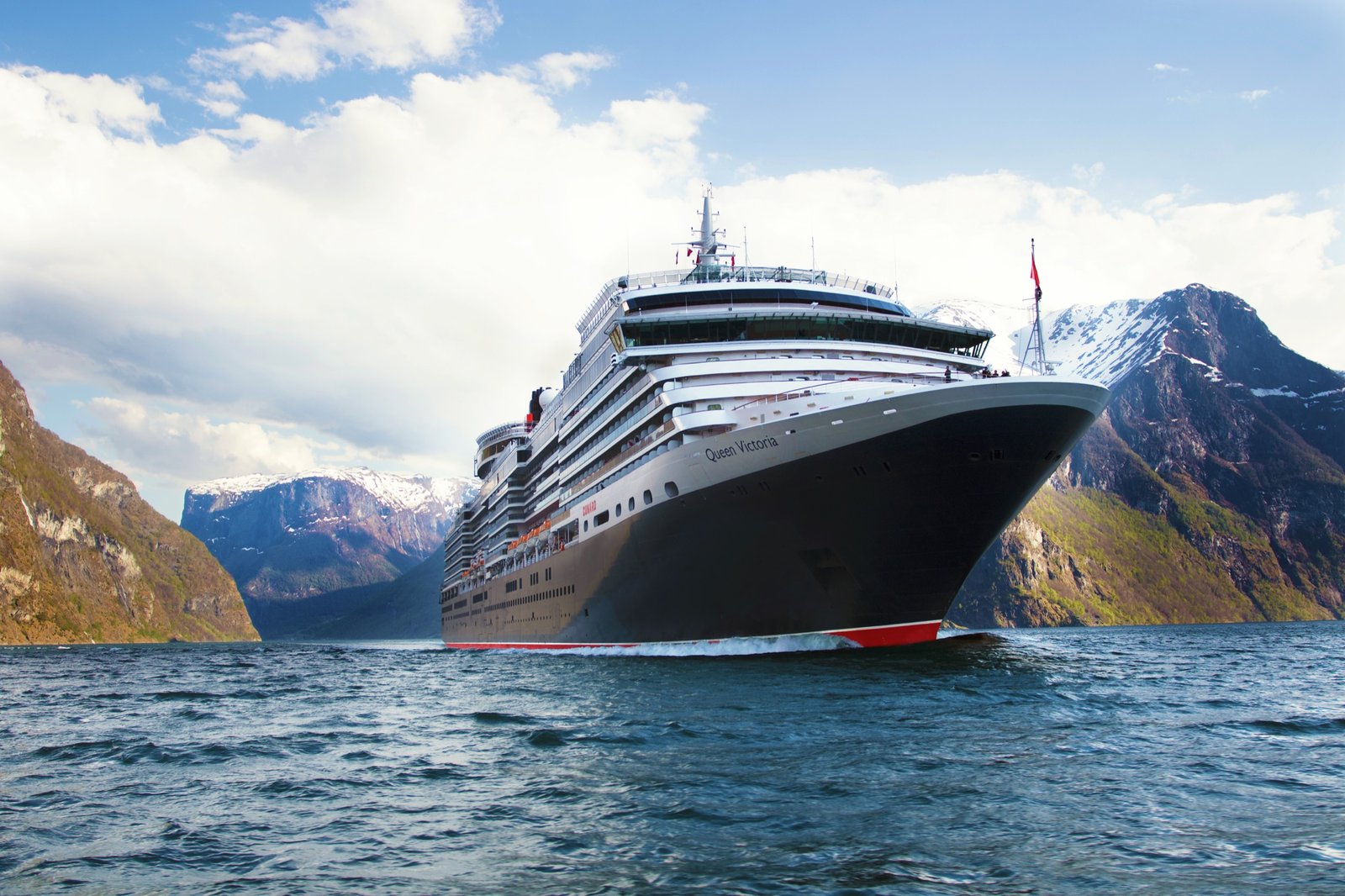 Cunard&rsquo;s Queen Victoria in a Norwegian fjord, snow-covered peaks either side