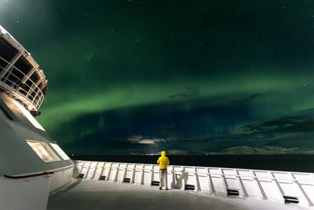 A guest on deck watching the northern lights from a Havila ship