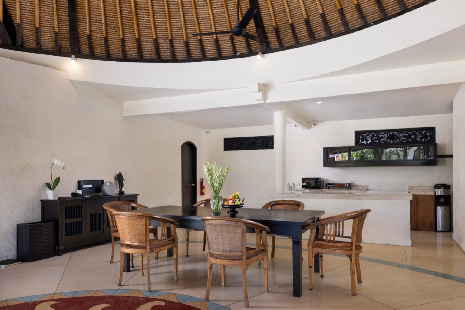 A villa dining table with chairs, open on one side to a courtyard.