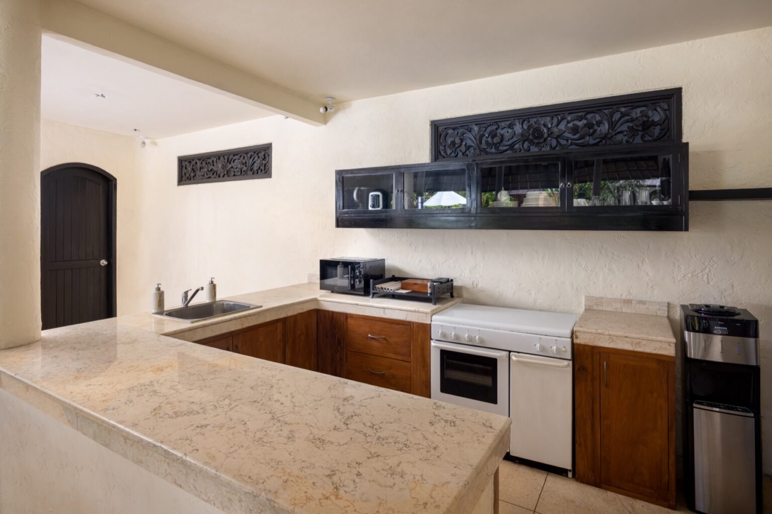 A villa kitchen with a stone counter, cabinetry and an oven.