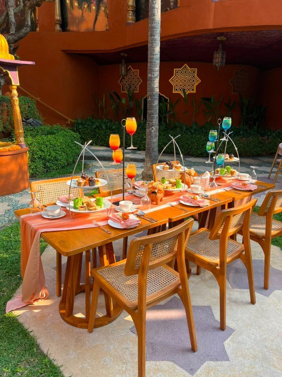 A long table in the spa courtyard set for afternoon tea, with tiered stands of food and coloured drinks in tall glasses.