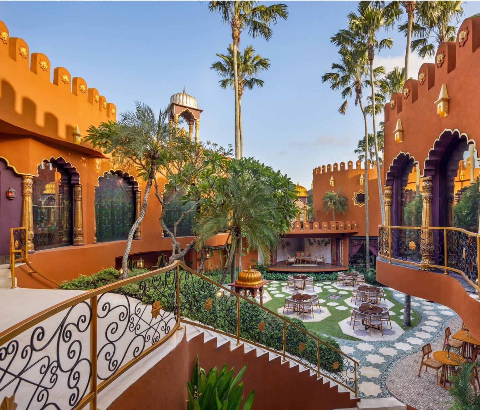 The spa building's terracotta walls, scalloped arches and gilded columns around a courtyard set with tables, under tall palms.