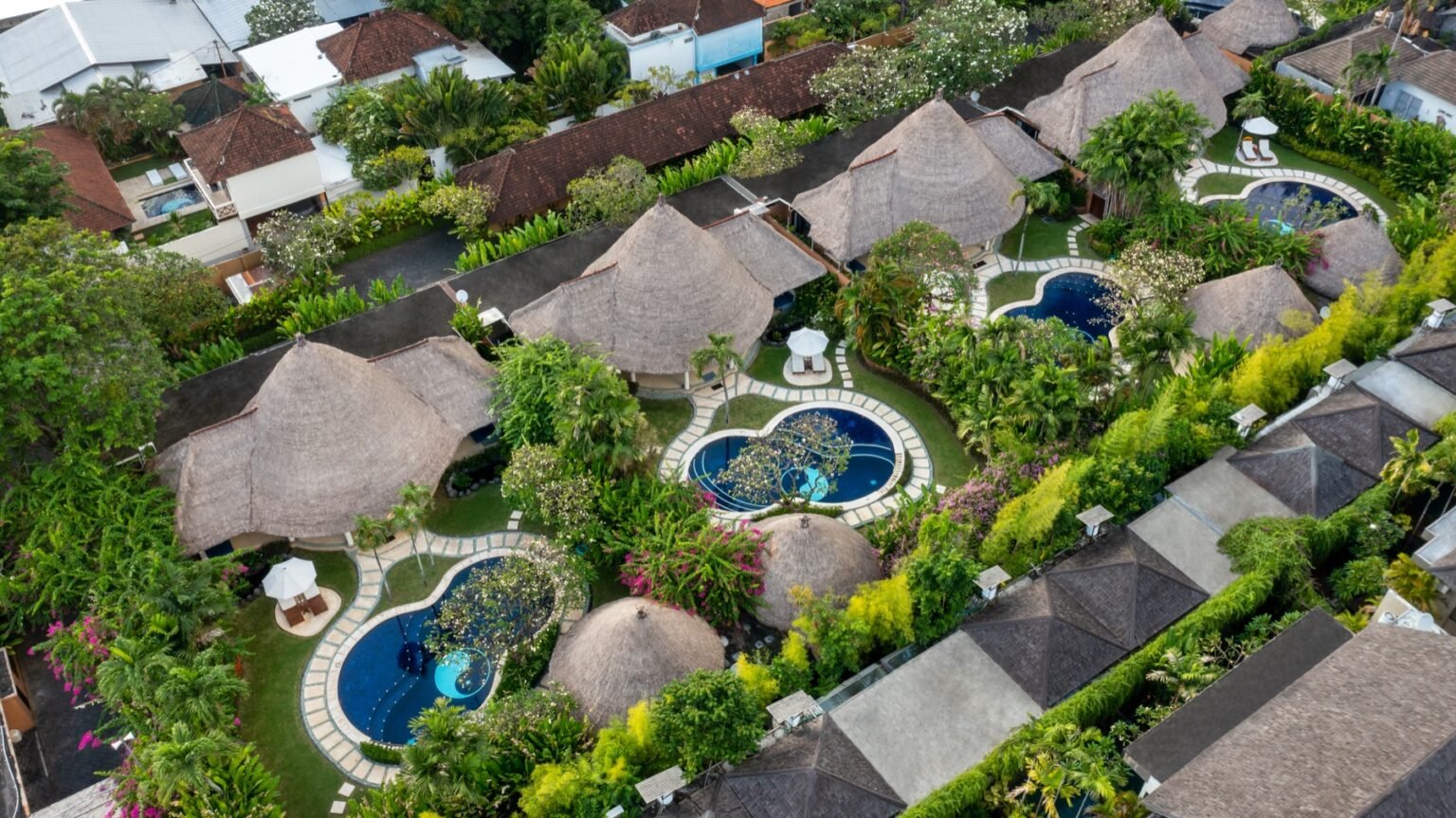 Two neighbouring villas photographed from above, each with its own pool and garden.