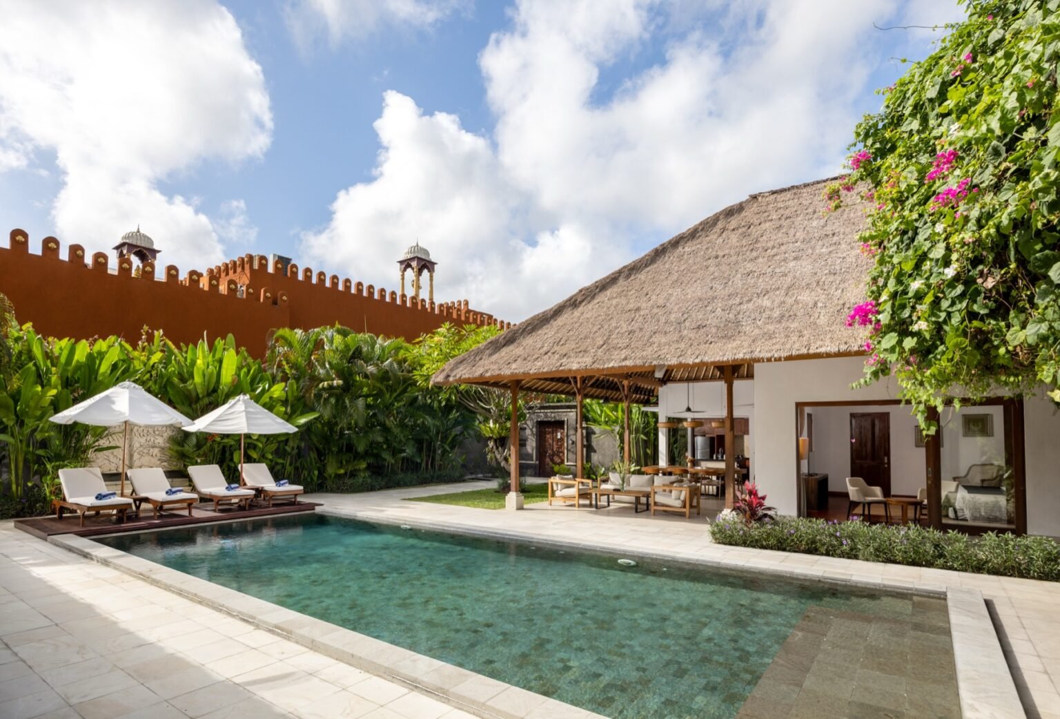 A villa pool running alongside a covered open-air living pavilion.