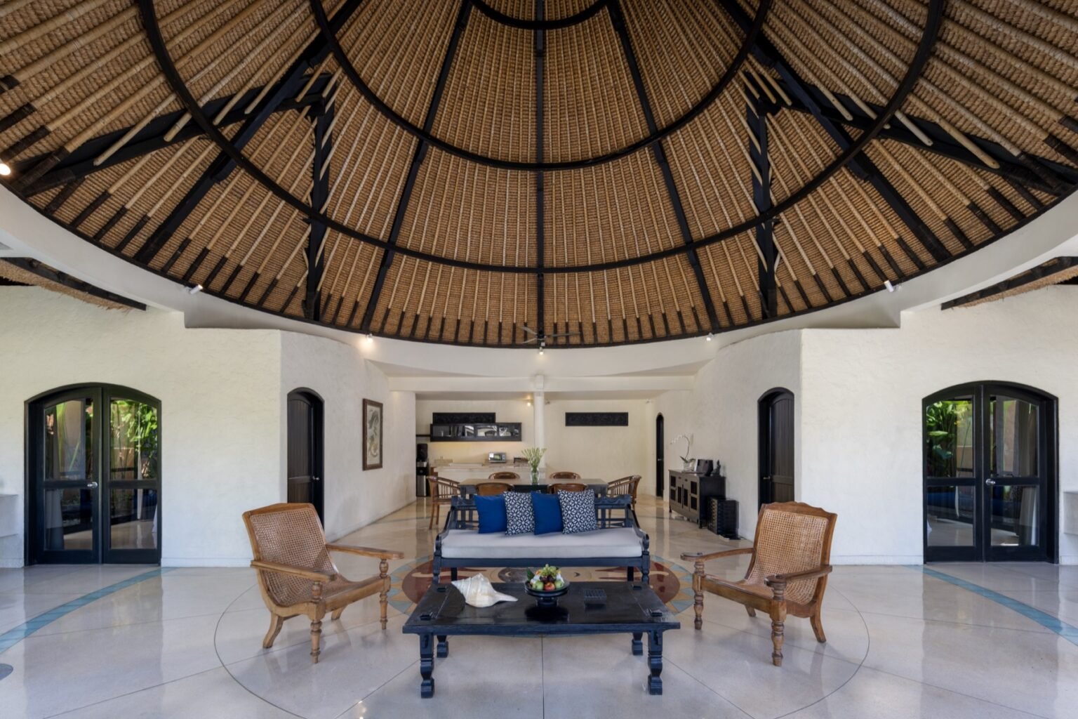 A villa living room open to the garden, with seating facing the pool.