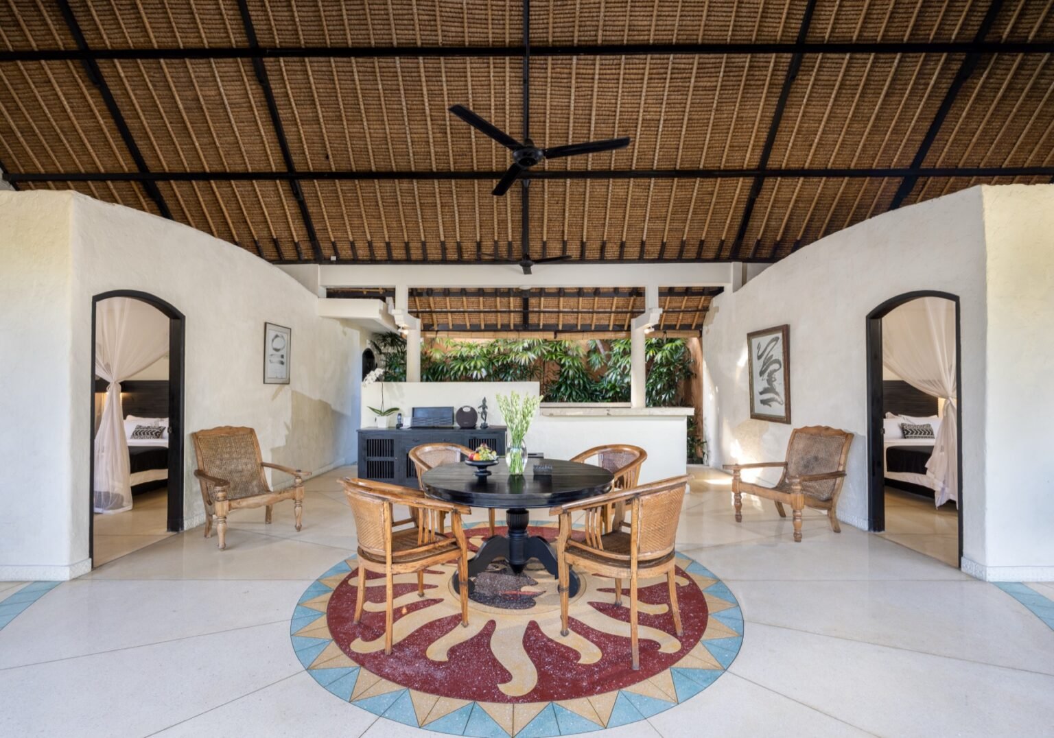 An open-plan villa living room with sofas, opening onto the pool terrace.