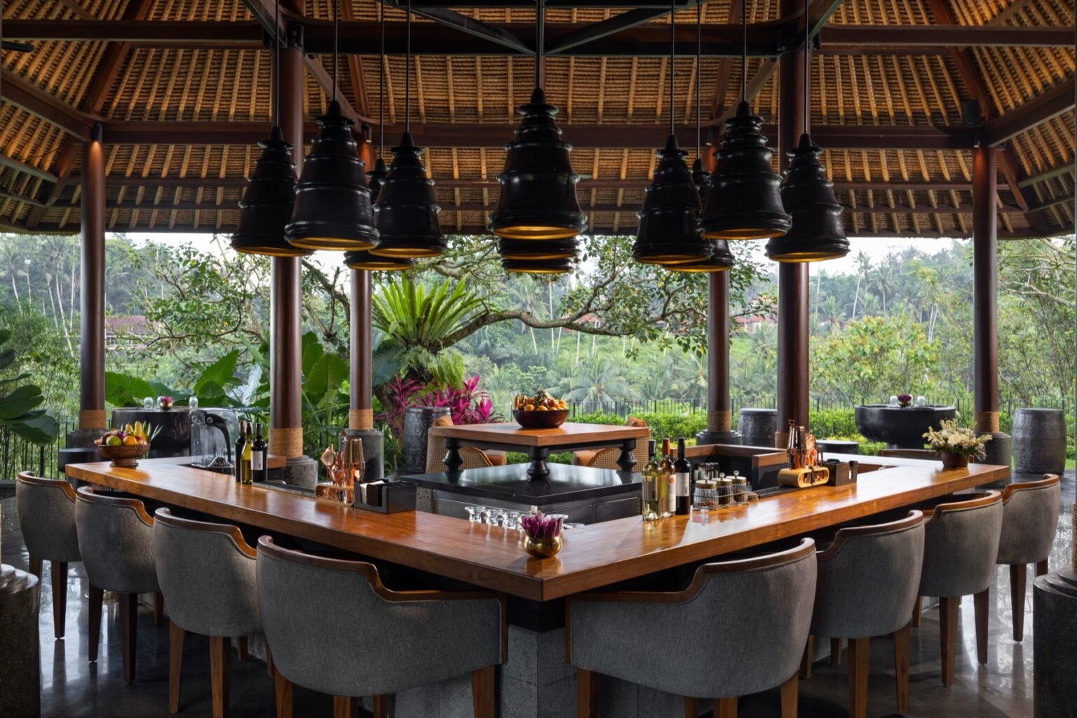A sunken bar counter with stools, set below floor level with jungle views behind.
