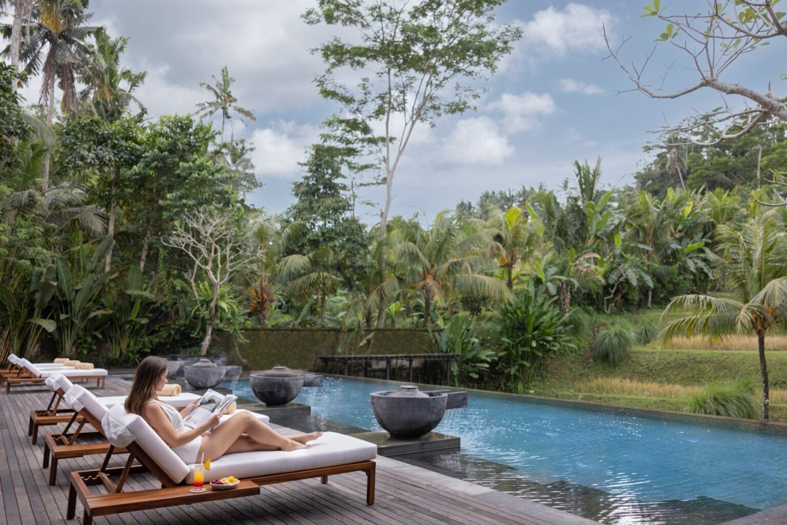 A swimming pool with sun loungers on the deck and planting around it.