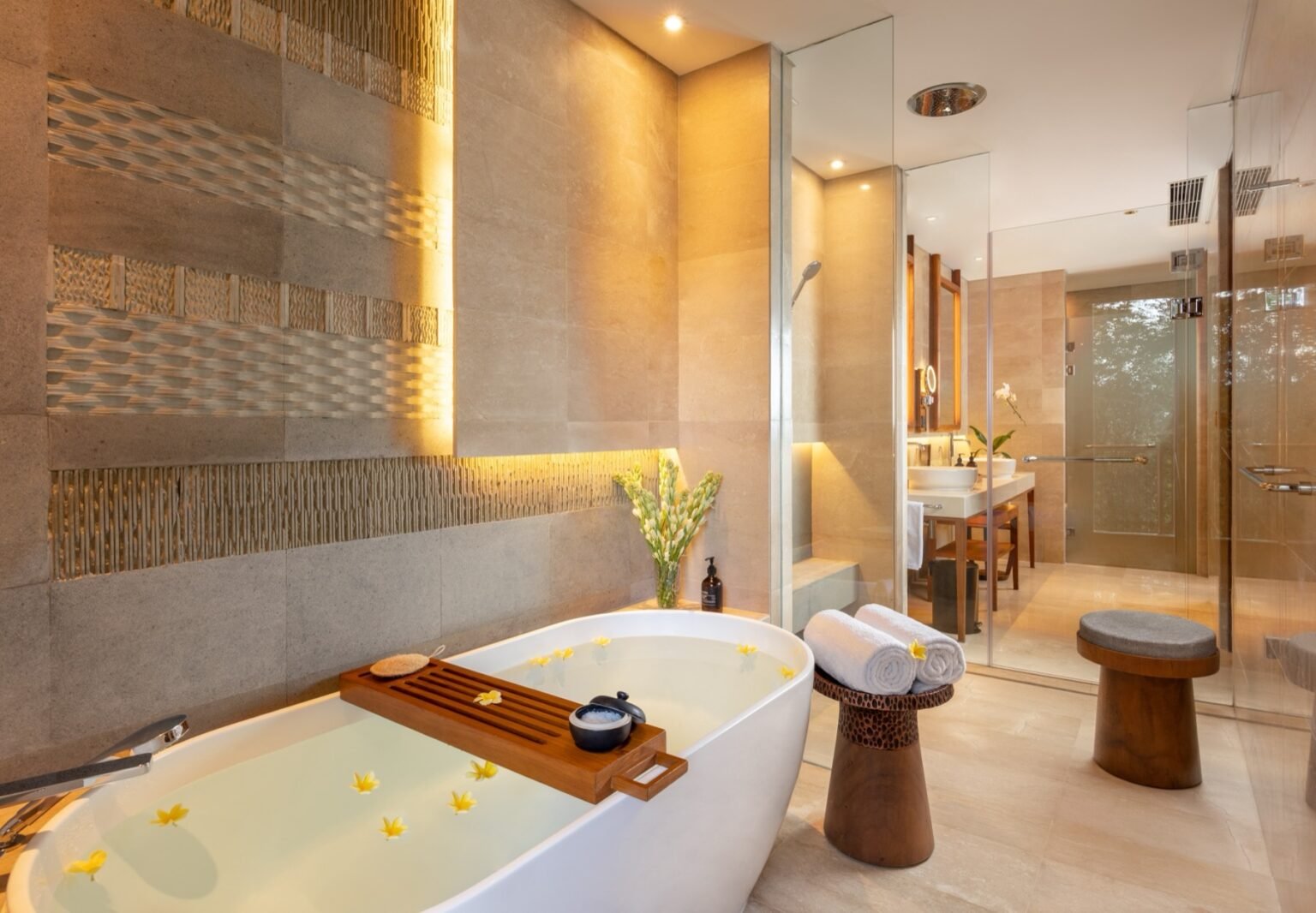 A bathtub set into a tiled surround beside a woven wall panel, with a shower alongside.