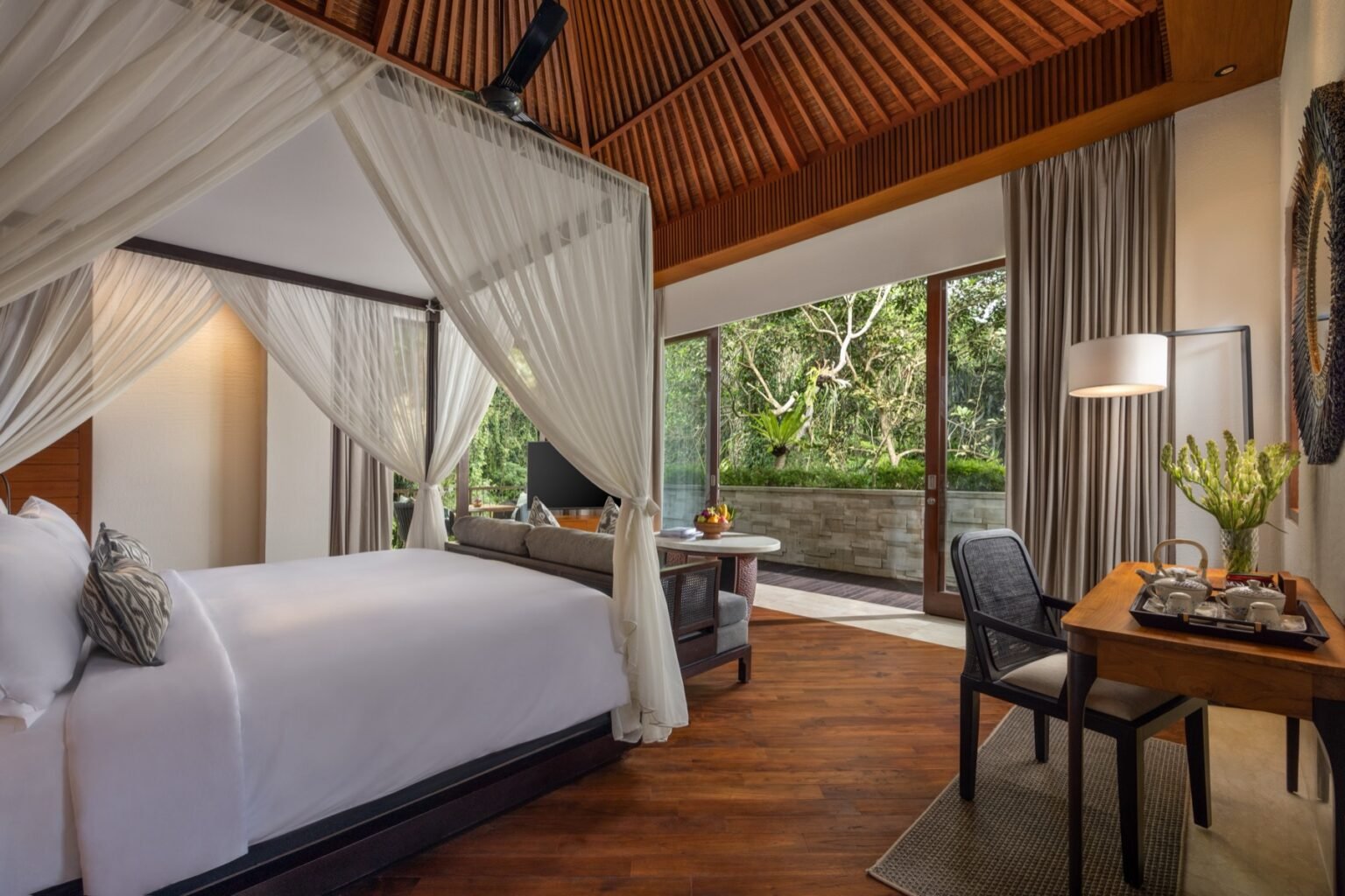 A villa living area with sofas and a dining table under a peaked timber ceiling.
