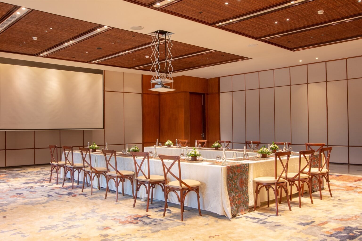 A function room with tables arranged in a U shape and a projection screen at the head.