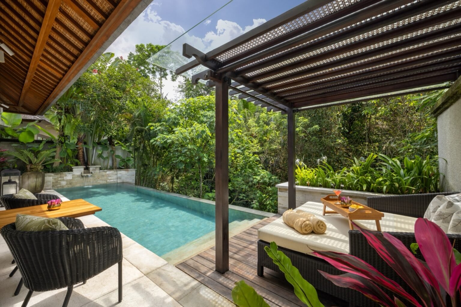 A villa bedroom with a four-poster bed opening onto a terrace and pool.