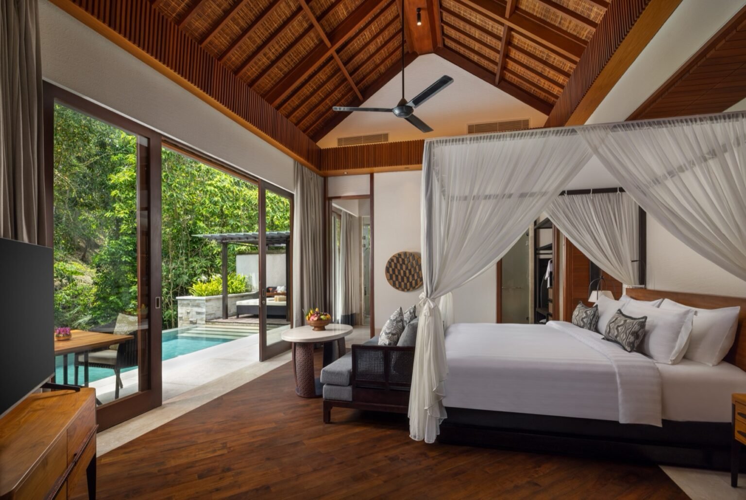 A villa with a private pool on its terrace, enclosed by garden planting.