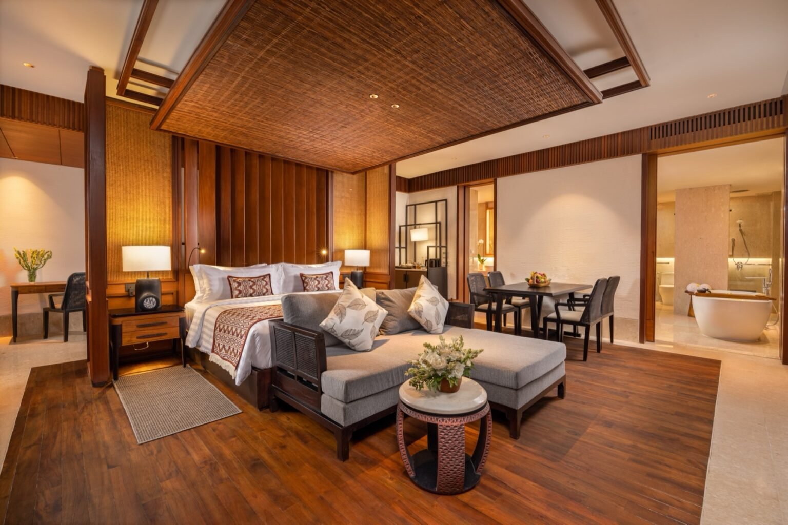 A suite with a bed, a sofa and an armchair, opening onto a balcony.