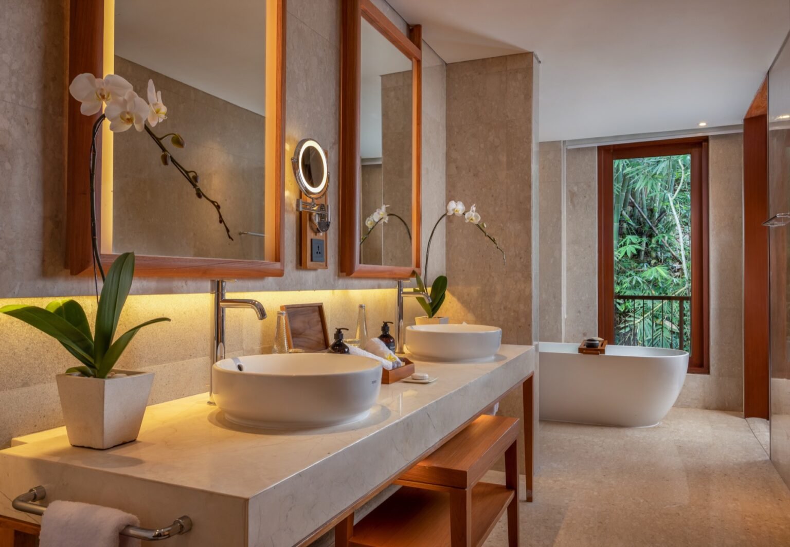 A bathroom with twin basins, an orchid on the counter and a freestanding bath beyond.