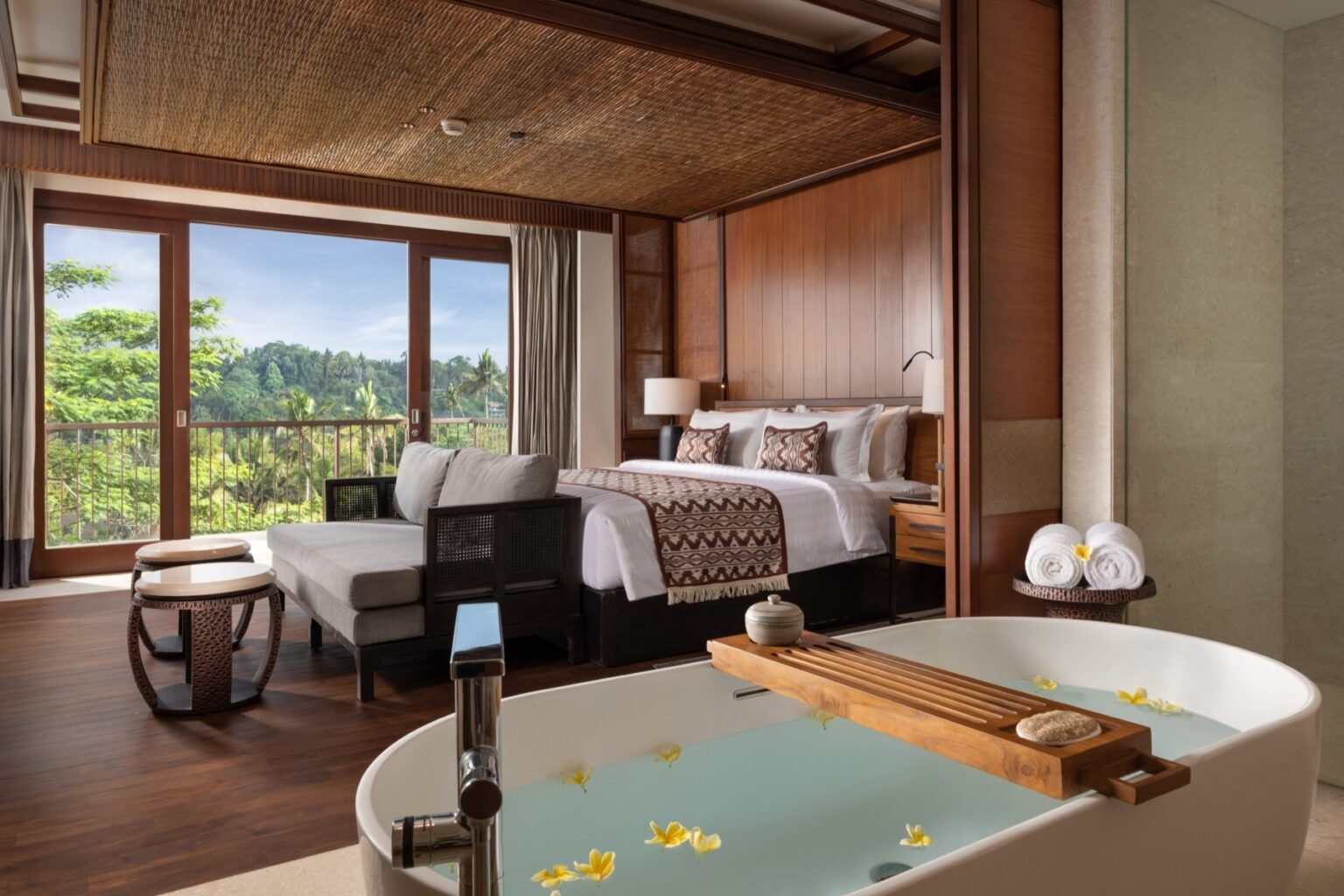 A suite with a bedroom and a separate living area under a high timber ceiling.