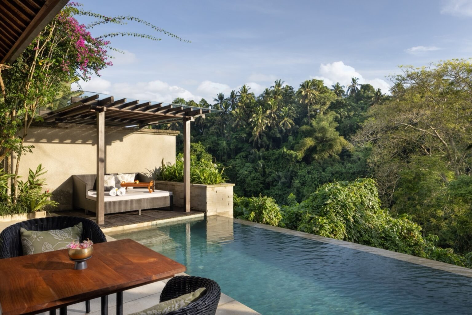 A villa bedroom with a four-poster bed, open on one side to the pool terrace.