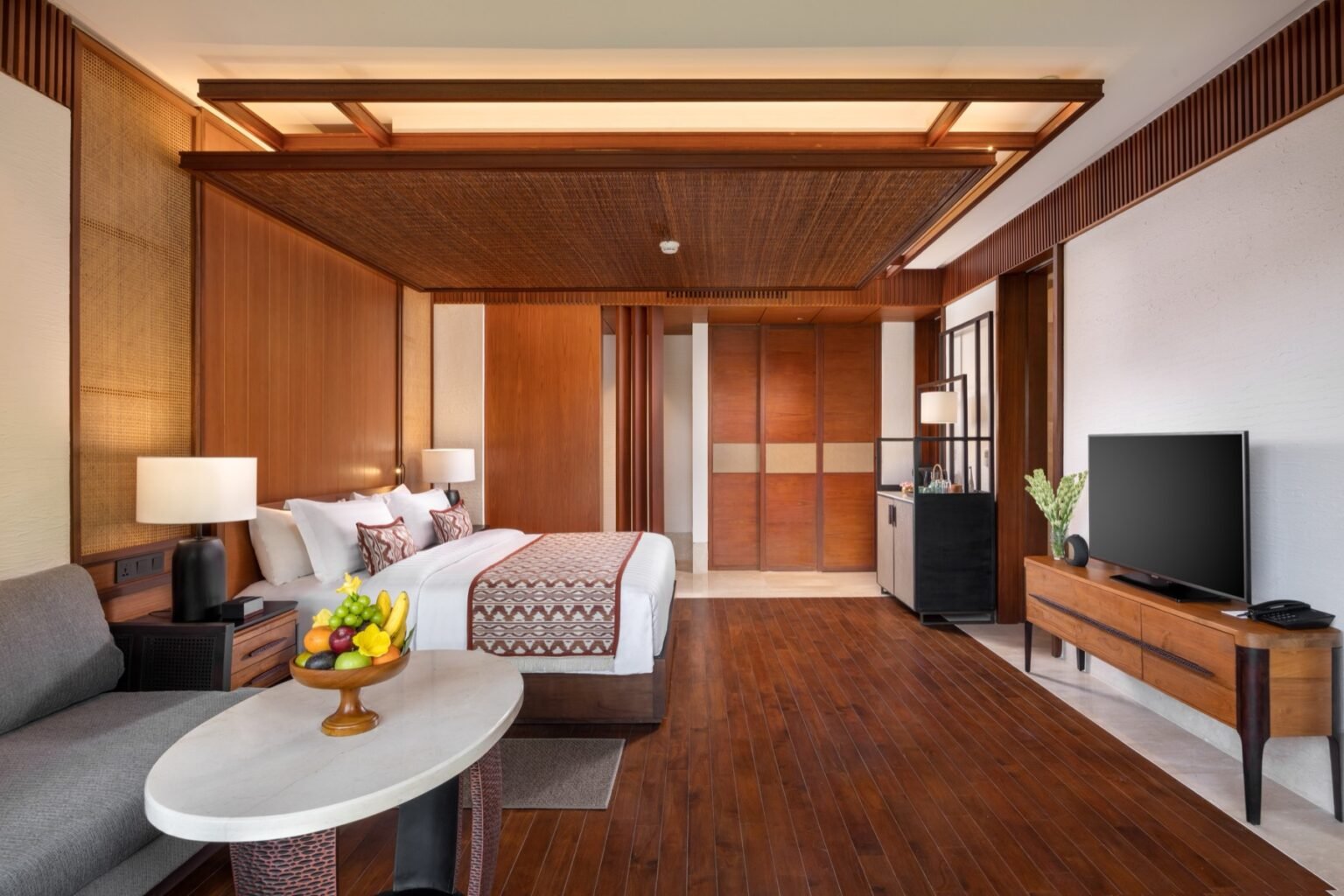 A suite living area with a sofa, armchairs and a round table on a timber floor.