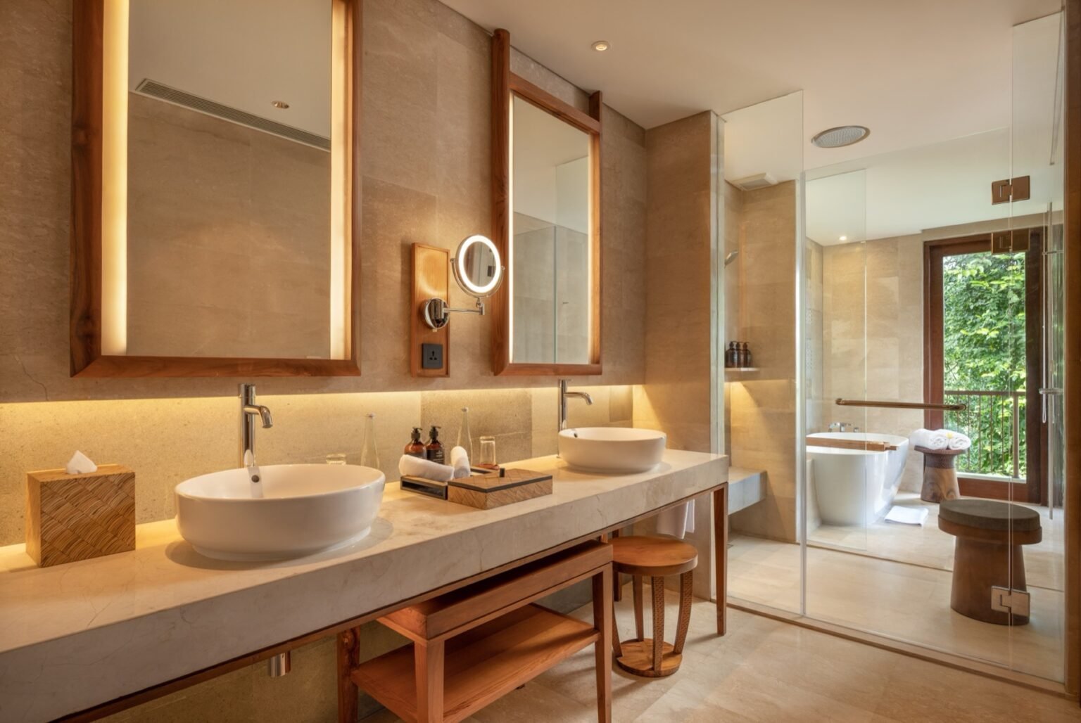 A bathroom with twin basins on a long counter, a mirror above and a shower beyond.