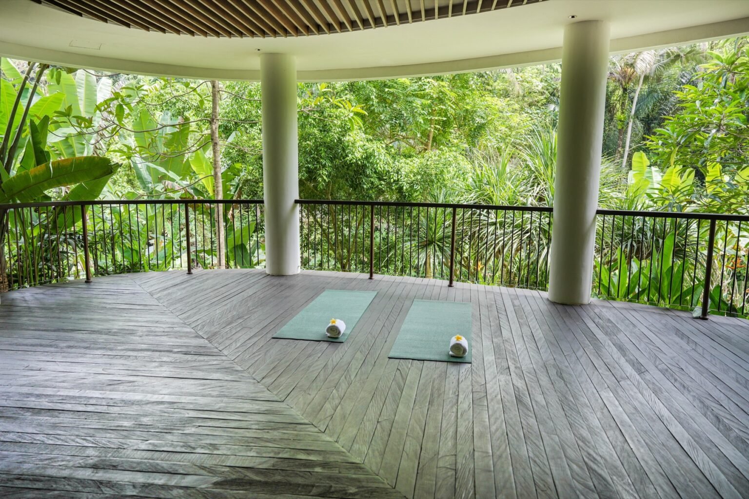 An open-sided yoga pavilion with mats laid out, surrounded by jungle.