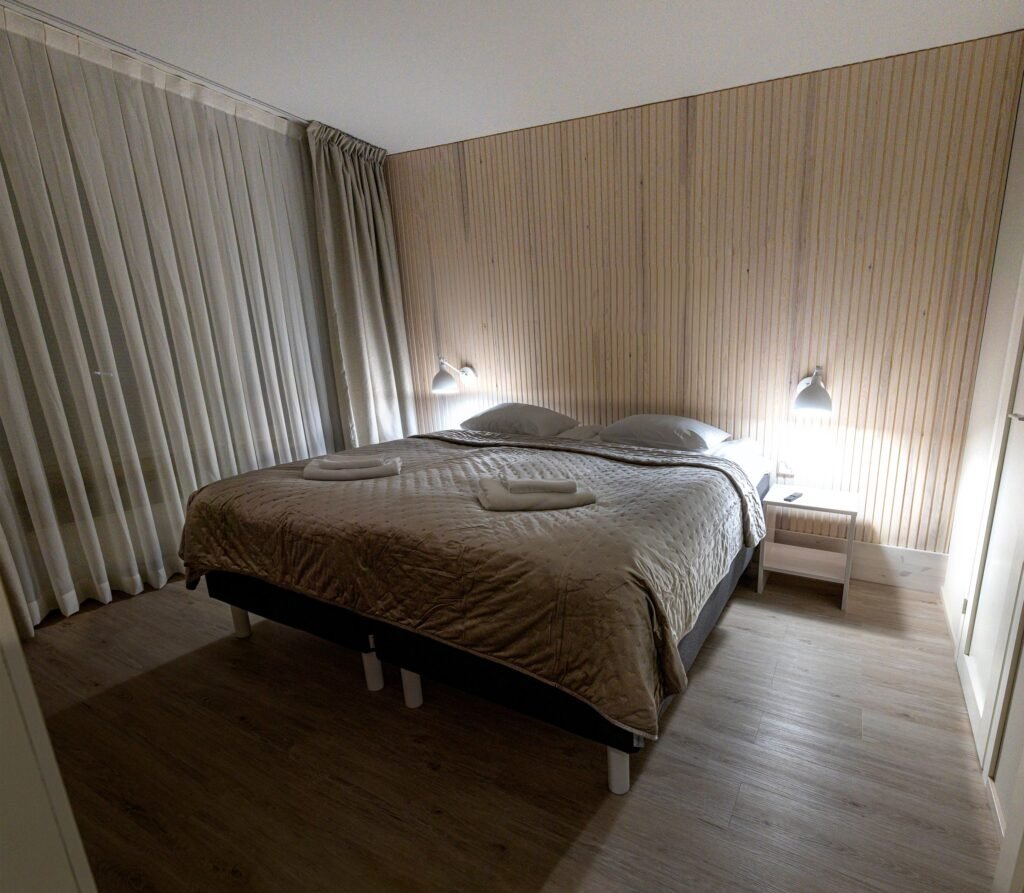 A double bed with reading lights in a bedroom of a two-bedroom apartment