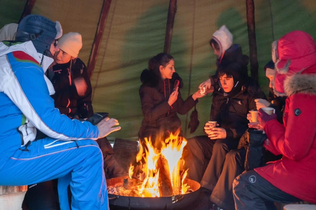 People warming themselves around a fire inside a Lappish tent