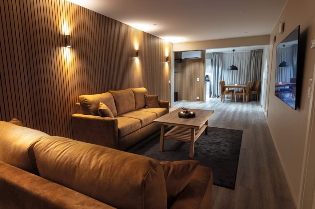 A living room with sofas looking through to the dining table and kitchen beyond