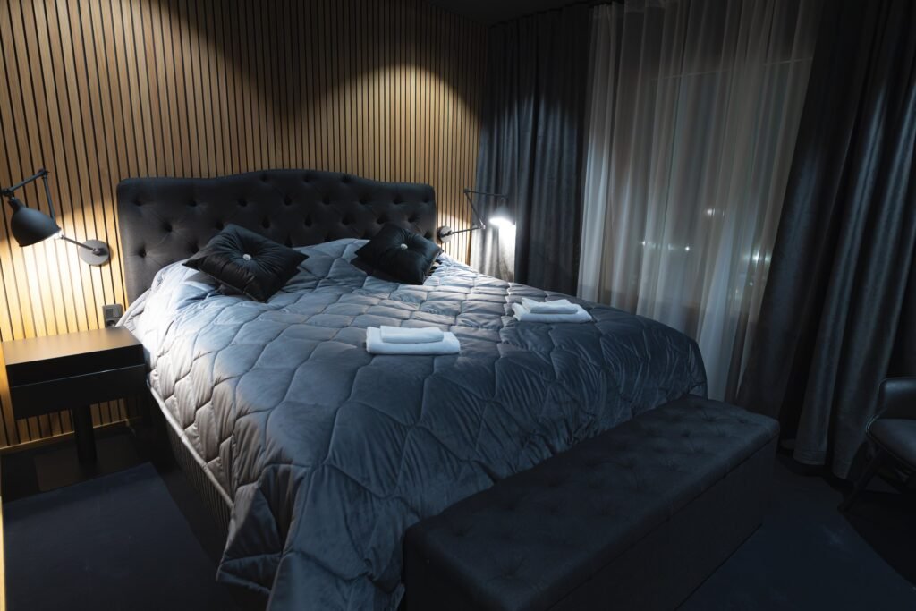 A double bed with a buttoned headboard against a timber-panelled wall