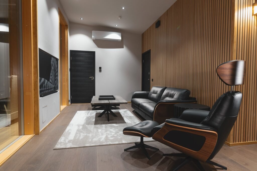 A living room with leather armchairs and a timber-panelled wall in a luxury apartment in central Rovaniemi