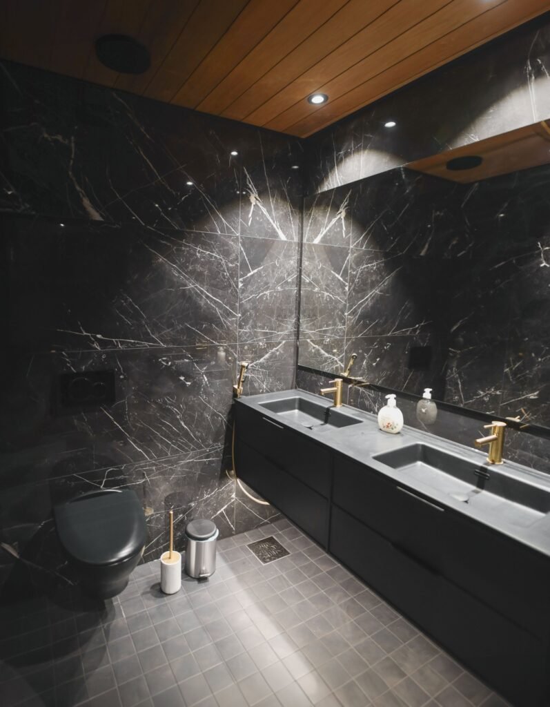 A black marble bathroom with a double vanity and brass taps in a luxury apartment in central Rovaniemi
