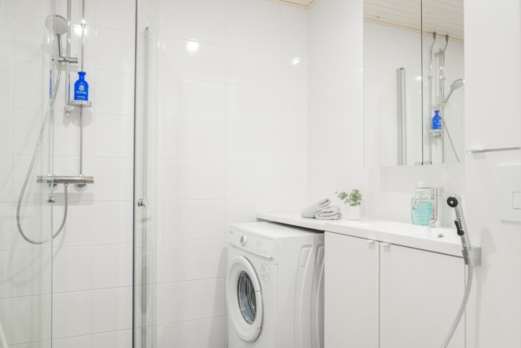 A bathroom with a shower and a washing machine in a studio apartment in central Rovaniemi
