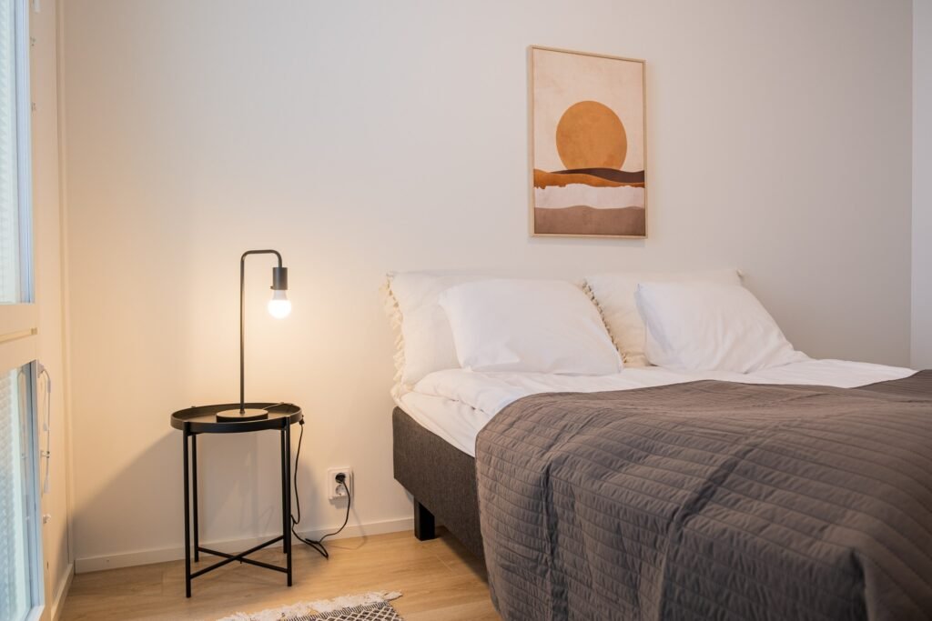 A bed and bedside lamp in a studio apartment in central Rovaniemi