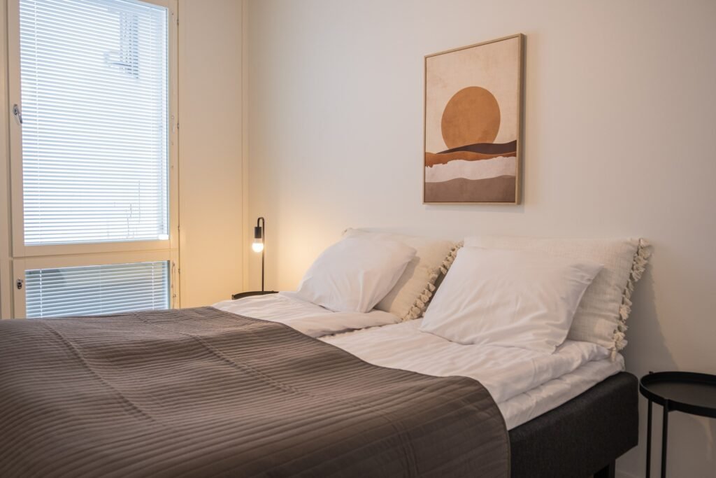 A bed beside the balcony window of a studio apartment in central Rovaniemi