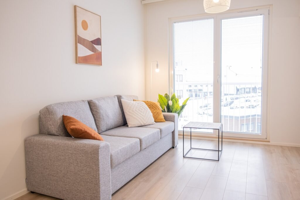 The living area of a studio apartment in central Rovaniemi, with a sofa and a balcony door