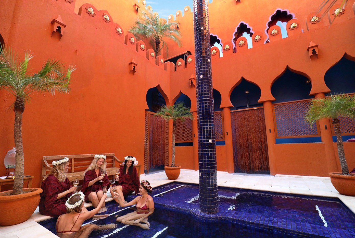 A group in robes and flower crowns gathered around the plunge pool in the spa courtyard.
